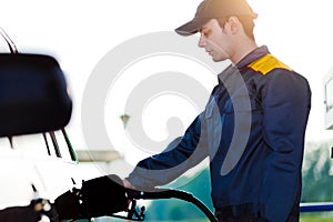 Gas station worker refilling car at service station