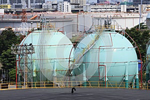 Gas storage tank in oil refinery industry site with urban scen b