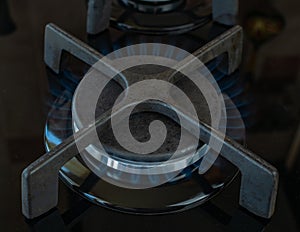 Gas stove burner burning with a blue flame. Modern gas stove for cooking. Close-up of a burning gas burner. The concept