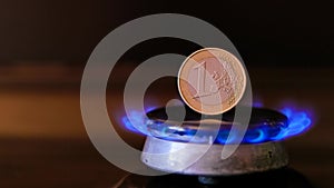 gas stove burner with one euro coin standing vertically on top, burning natural gas with blue flame