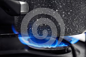 Gas stove with an open blue flame, cook on it dish in ladle