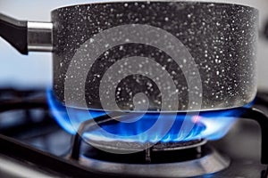 Gas stove with an open blue flame, cook on it dish in ladle