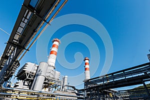 Gas turbine power plant on natural gas with chimneys of red-white color against a blue sky on a sunny day