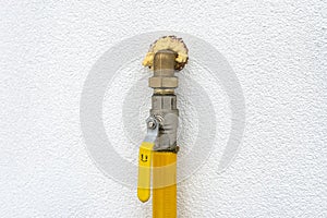 Gas valve located on the facade of the building, supplying gas to the boiler room, with a yellow handle. photo