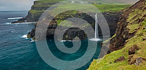 Gasadalur waterfall wide angle panorama in Faroe Islands, misty day