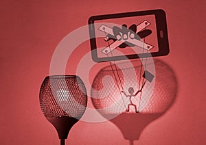 Gaslight with silhouette of puppet on strings being manipulated by a hand in mobile phone cast by the lamp on wall