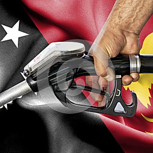 Gasoline consumption concept - Hand holding hose against flag of Papua New Guinea