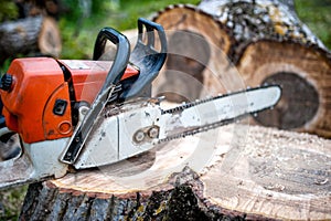 Gasoline powered professional chainsaw on pile of cut wood