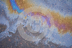 Gasoline spot on wet asphalt. Multi colored oil spill on asphalt road, abstract background, texture