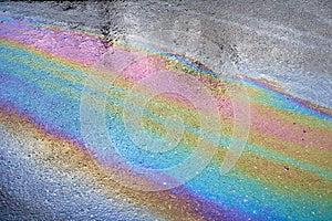 Gasoline spot on wet asphalt. Multi colored oil spill on asphalt road, abstract background, texture.