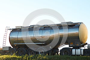 Gasoline tank truck on the road with open cabine door and trucker in it