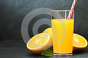 Gass of fresh orange juice with fresh fruits on dark table