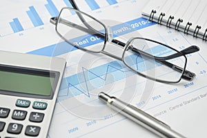 Gasses pen and calculator on financial chart and graph