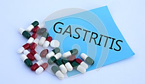 GASTRITIS words on a blue sheet of paper against the background of multicolored tablets