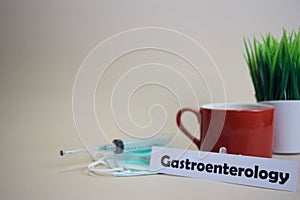 Gastroenterology text, grass pot, coffee cup, syringe, and face green mask. photo