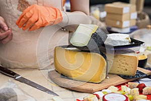 Gastronomic products for gourmets, traditional italian cut cheese heads on market counter, woman hands of seller with photo