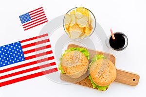 Gastronomical tourism with american flag and burgers, chips, coke on white background top view