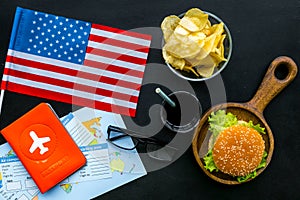 Gastronomical tourism with american flag, passport, tickets, map, burgers, chips, coke on black background top view