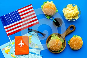 Gastronomical tourism with american flag, passport, tickets, map, burgers, chips, coke on blue background top view