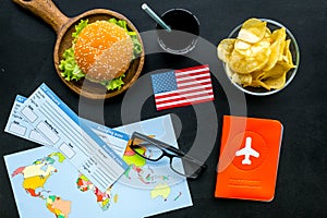 Gastronomical tourism with american flag, passport, tickets, map, burgers, chips, drink on black background top view
