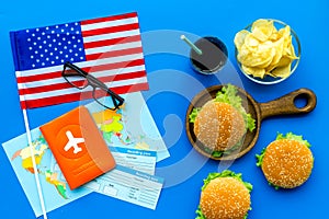 Gastronomical tourism with american flag, passport, tickets, map, burgers, chips, drink on blue background top view
