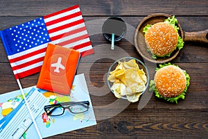 Gastronomical tourism with american flag, passport, tickets, map, burgers, chips, drink on wooden background top view