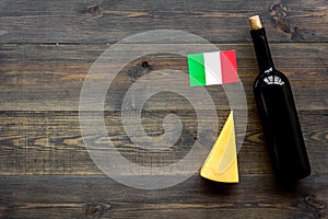 Gastronomical tourism. Italian food symbols. Italian flag, cheese parmesan and bottle of red wine on dark wooden