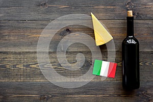 Gastronomical tourism. Italian food symbols. Italian flag, cheese parmesan and bottle of red wine on dark wooden