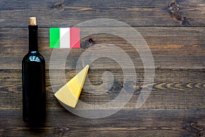 Gastronomical tourism. Italian food symbols. Italian flag, cheese parmesan and bottle of red wine on dark wooden