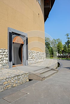 Gate of circular earthed dwelling building in blue sky