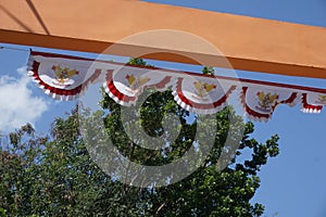 A gate at the entrance of a village has a red and white flag umbul umbul attached which is the Indonesian flag