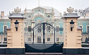 Gate iron entrance of an old blue baroque building with lawn, decorative tree and boxwood bushes, Mariinsky Palace in Kiev,