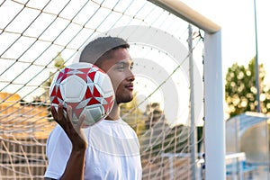 gate keeper throwing foot ball looking away at dusk in soccer field