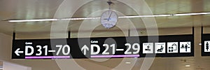 Gate numbers, directions, and an analog clock inside an airport terminal