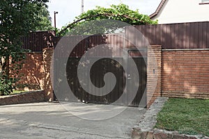 Gate and part of the fence of bricks and metal in the wall on a city street