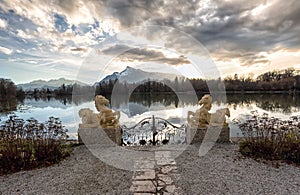 Gate with sculptures at a lake during sunset photo