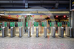 gates, gates, or turnstiles for accessing the train at the railway station with red signs.