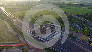 Gates of toll collection area with few cars entering highway, green field around