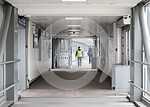 People including man in hi viz walking through a modern light tunner walkway