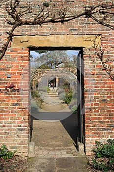 Gateway in brick wall in cottage garden.