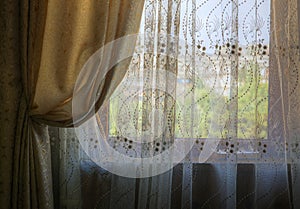 Gathered curtains and blinds on the window of the room