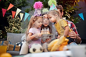 Gathered young family blowing birthday candles together. birthday, togetherness concept