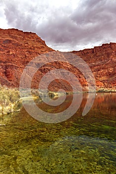 Gathering dark clouds near the Colorado river and the sandstone mountains, Lees Ferry landing, Page, AZ, USA