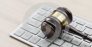 Gavel at the computer keyboard: Legal and law concept. Wooden hammer of justice and order