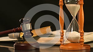Gavel dropping on sounding block beside hourglass and bible
