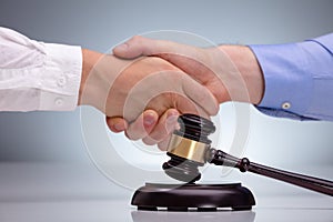 Gavel In Front Of Two Men Shaking Hands