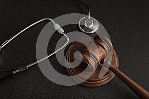 Gavel hammer of judge and stethoscop on black background. Sentence on medical negligence photo