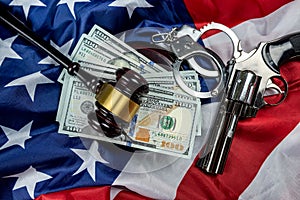 Gavel and handcuffs and money and gun on the background of the American flag of the USA.
