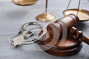 Gavel, handcuffs and scales of justice on grey wooden table. Criminal law