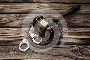 Gavel of the judge, handcuffs for the detention of criminals against the background of a wooden table.